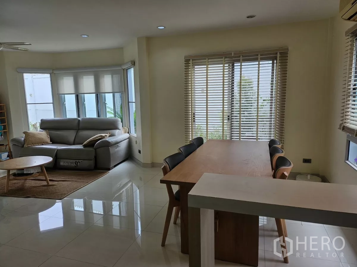 Detached House for rent in Khlong Toei, Bangkok - Open-plan lounge with floor-to-ceiling windows, grey sofa and coffee table overlooking greenery.