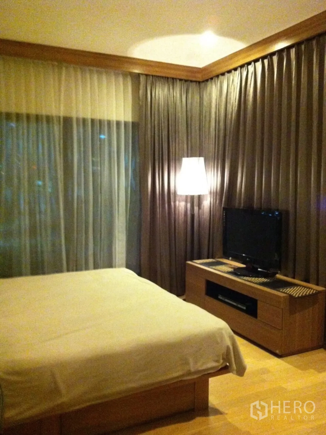 Condominium for rent or sale in Watthana, Bangkok - Master bedroom with bed, TV cabinet, sheer drapes and a standing floor lamp.