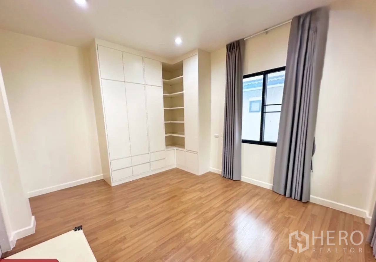 Detached House for sale in Lam Luk Ka, Pathum Thani - Spacious bedroom with built-in wardrobes, corner shelves, window and curtains.