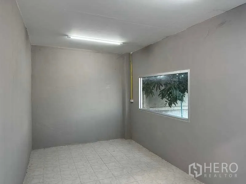 Warehouse for rent in Mueang Pathum Thani, Pathum Thani - Small office room with window and fluorescent lighting inside the warehouse.