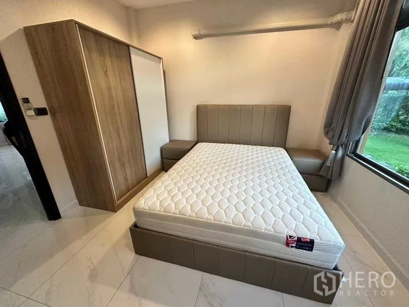 Detached House for rent in Lat Krabang, Bangkok - Ground-floor bedroom with upholstered bed, wardrobe and garden-view window.