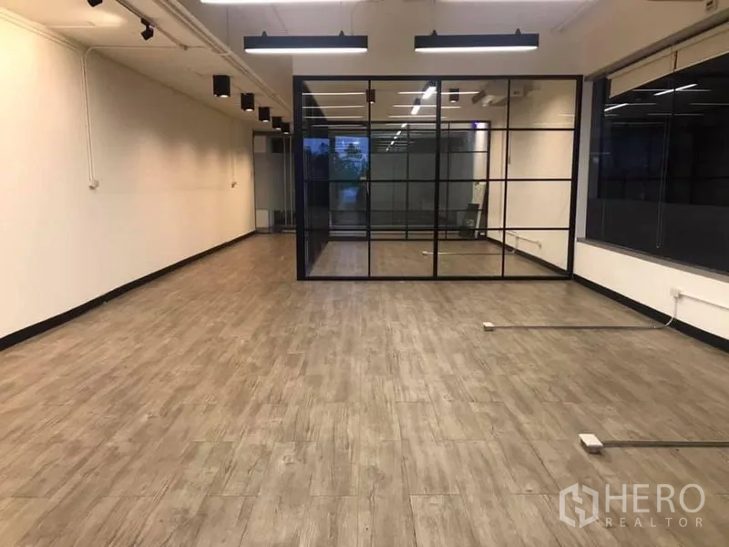 Office Space for rent in Khlong Toei, Bangkok - Spacious 80 sqm workspace with black-framed glass divider, LED track lights, and open layout.