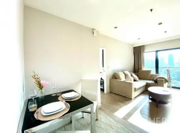 Condominium for rent in Khlong Toei, Bangkok - Sunlit living and dining space with neutral décor and a floor-to-ceiling balcony window.