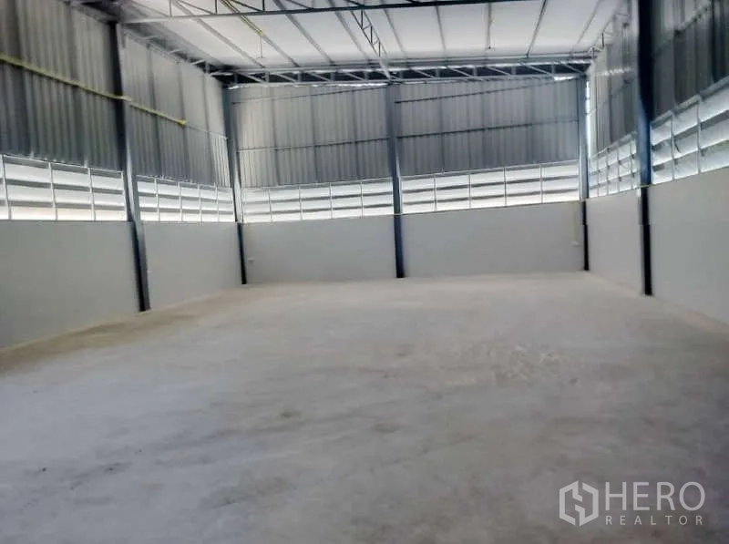 货栈 出租在Pathum Thani - 仓库内部空间开阔，层高高，钢结构梁架与平整混凝土地面。