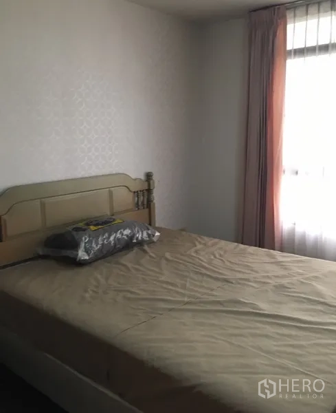 Condominium for rent in Watthana, Bangkok - Cozy guest bedroom with a bed, soft drapes and natural light from a tall window.