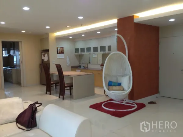 公寓 出租在Bang Rak, Bangkok - 开放式起居与厨房空间，带中岛、筒灯以及白色蛋形吊椅的邦拉区公寓。