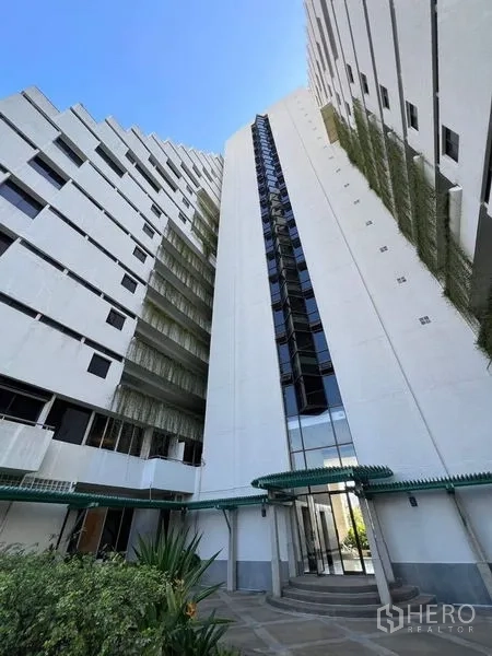 Condominium for rent or sale in Watthana, Bangkok - High-rise condominium exterior with glass entrance and white facade.