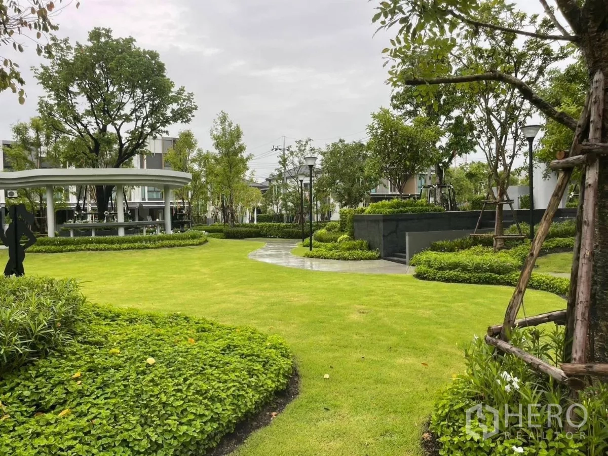 Townhouse for rent in Samut Prakan - Lush central garden with manicured lawns, trees and a curved walking path inside the estate.