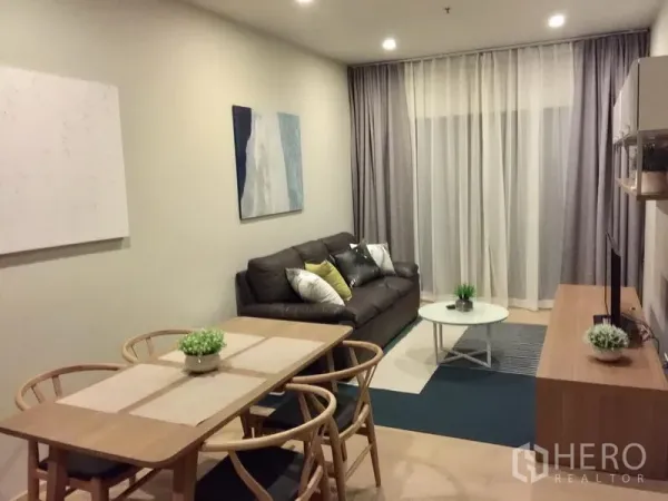 Condominium for rent in Bangkok - Cozy lounge with leather sofa, wall art, round coffee table and sheer blackout drapes in a contemporary condominium.