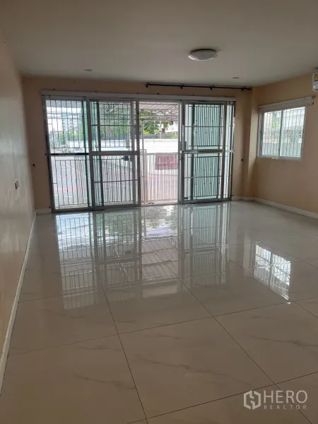 Townhouse for rent in Huai Khwang, Bangkok - Spacious ground-floor room with floor-to-ceiling sliding doors and security grilles.
