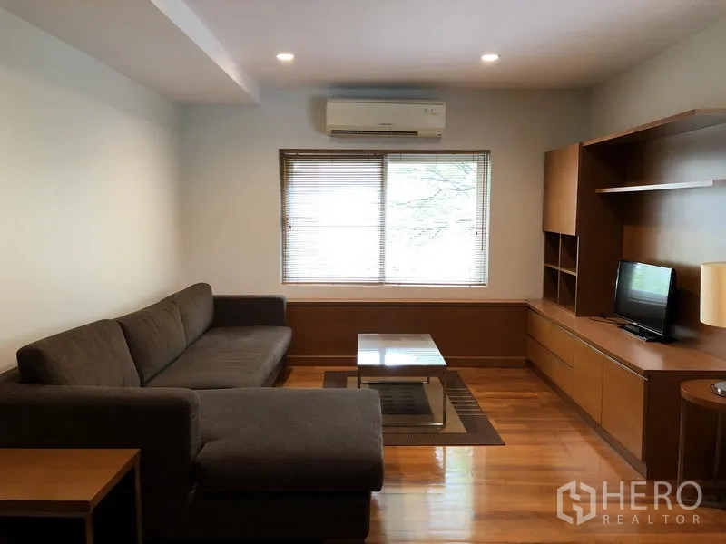 独立式住宅 出租在Watthana, Bangkok - 舒适家庭厅，L型沙发、定制电视柜与木地板。