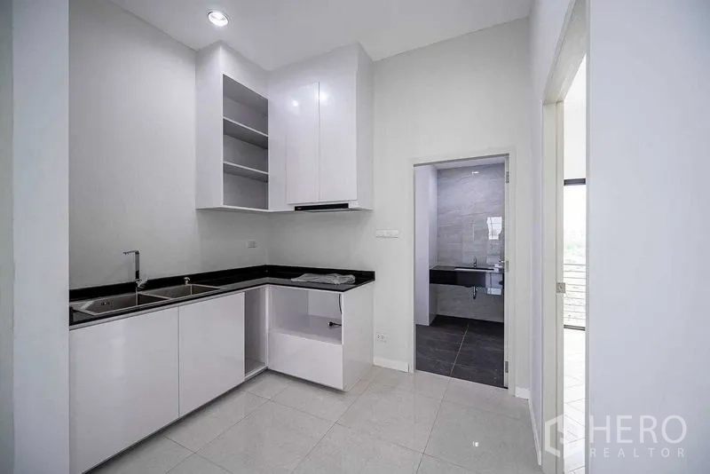 带办公室的家 出租在Suan Luang, Bangkok - L形茶水间，白色柜体黑色台面，旁边为卫生间门。