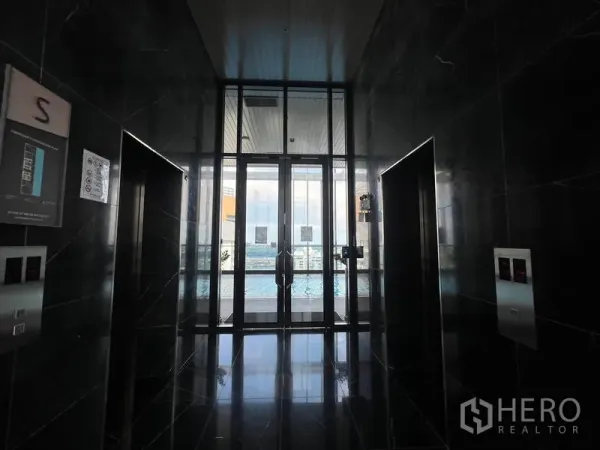 Condominium for sale - Sleek elevator lobby with black marble walls and glass doors opening to the pool deck.