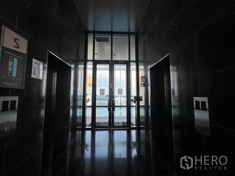 Condominium for sale - Sleek elevator lobby with black marble walls and glass doors opening to the pool deck.