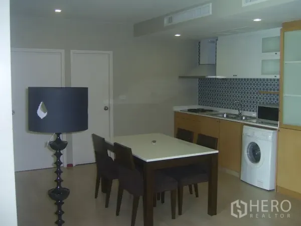 Condominium for rent in Khlong Toei, Bangkok - Open-plan kitchen with mosaic tile backsplash, washing machine, and a four-seat dining table.