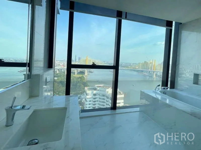 公寓 出租或出售在Bangkok - 大理石浴室，设浴缸和大窗，框景河城天际线。
