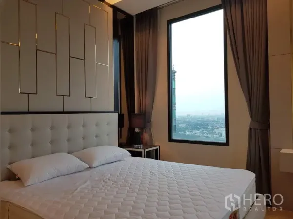 公寓 出租在Chatuchak, Bangkok - 主卧配软包床头与大窗，可欣赏曼谷乍都节天际线景观。