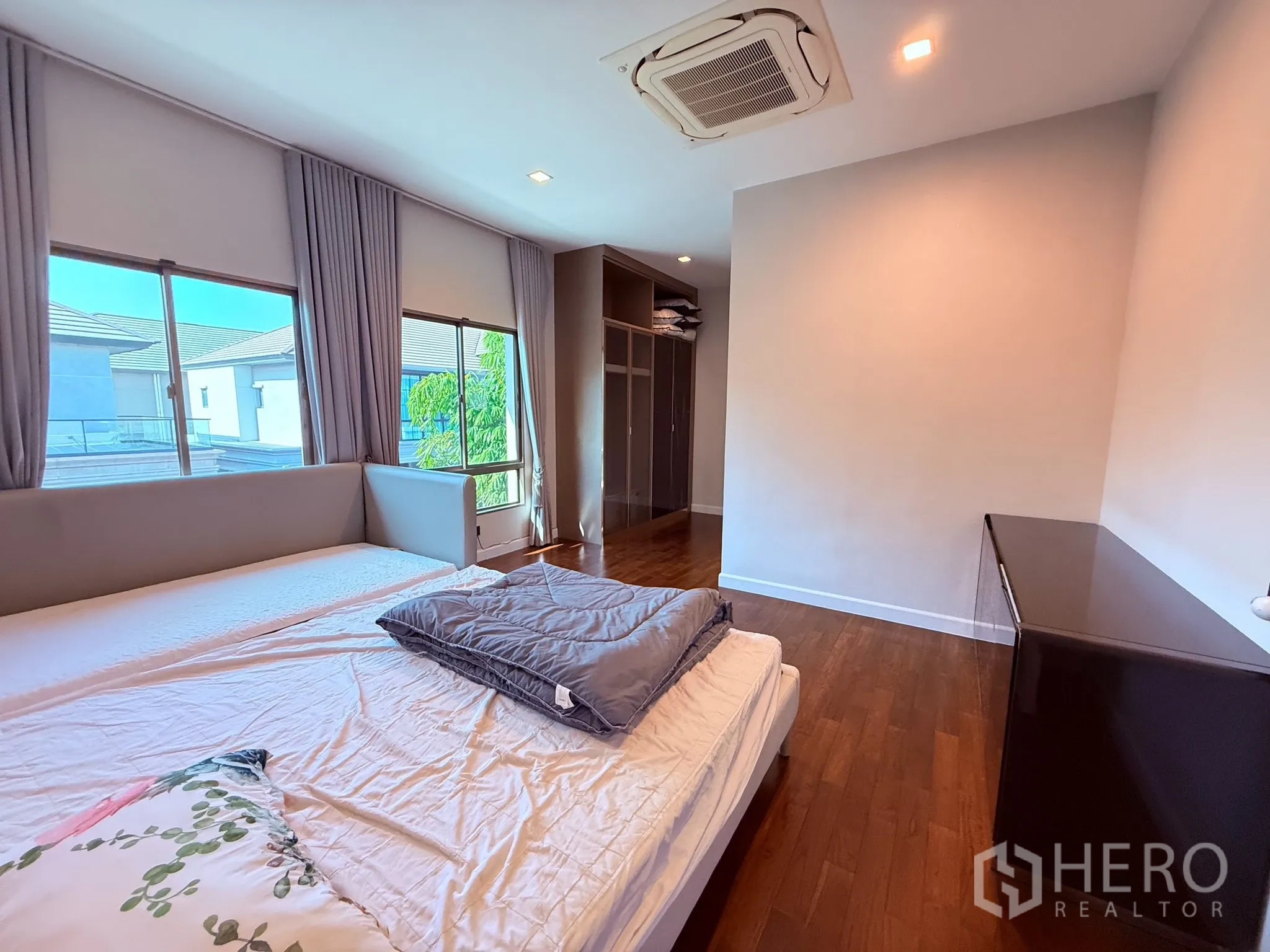 Detached House for rent or sale in Prawet, Bangkok - Spacious bedroom with hardwood floor, large windows, ceiling cassette AC, and built-in wardrobe.