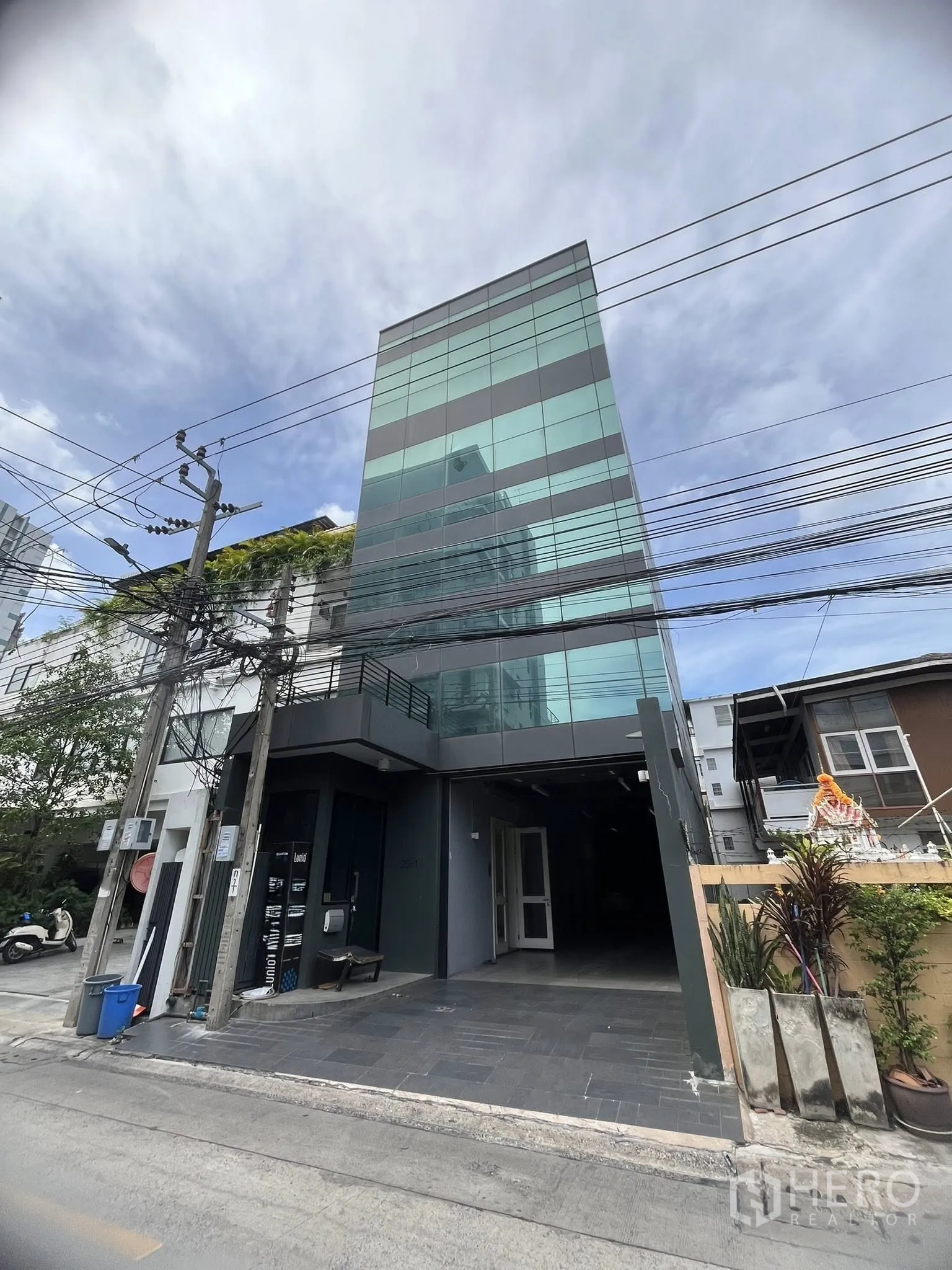 家庭办公室 for rent in Watthana, Bangkok - 现代玻璃外立面建筑，带有遮雨入口。