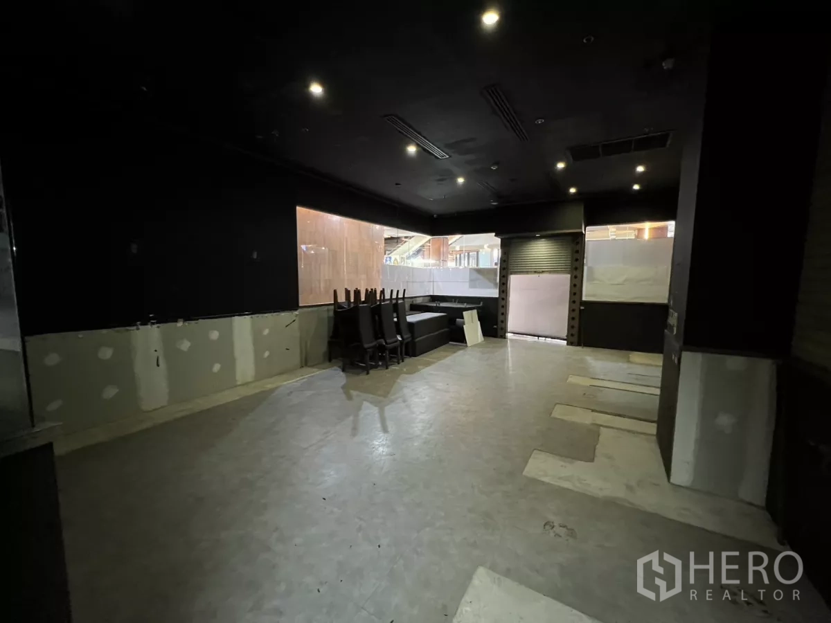 零售空间 出租 - 开放式深色吊顶空间，筒灯、卷闸门与大面积内窗。