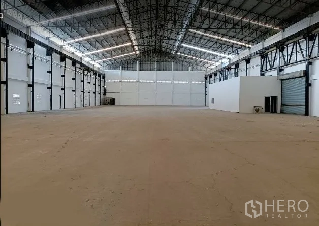 Factory for rent in Bang Phli, Samut Prakan - Spacious factory interior with high steel roof, skylight panels, smooth concrete floor, side office block and roller shutter door in Bang Phli, Samut Prakan.