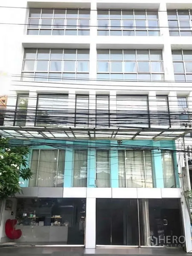 办公空间 出租在Bang Kapi, Bangkok - 多层商业建筑外立面，大面积方格窗与一层通透玻璃门面。