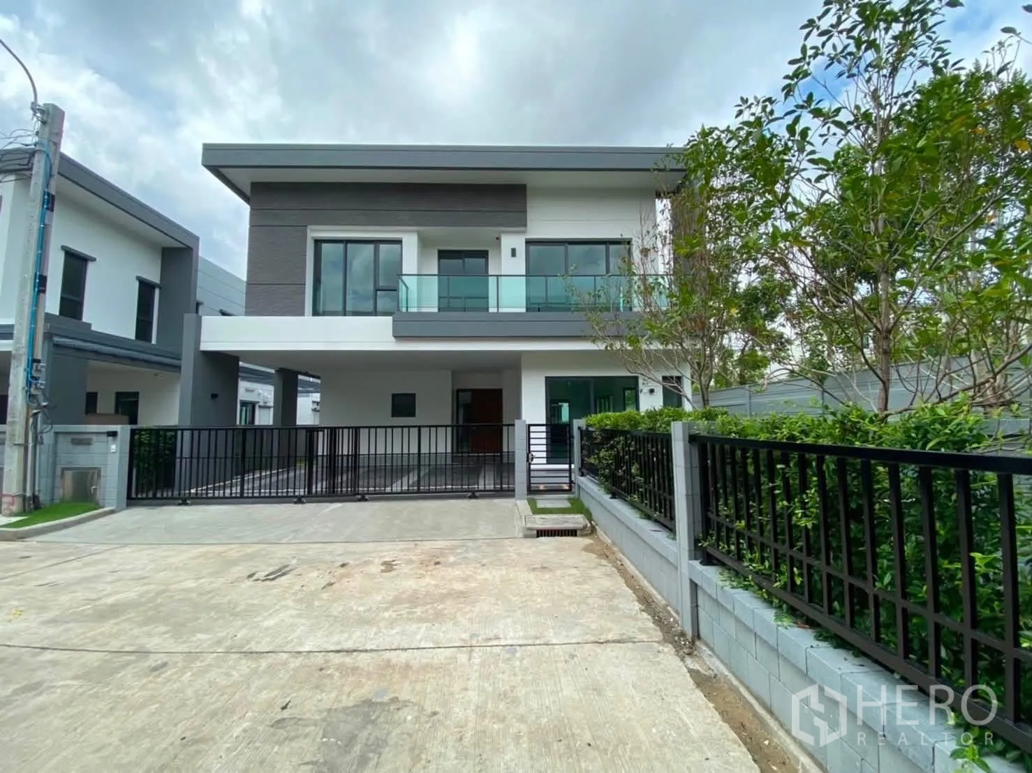 Detached House for rent or sale in Prawet, Bangkok - Modern two-storey detached house exterior with balcony, driveway gate, and landscaping.