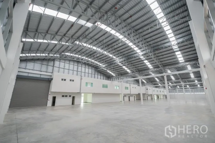 Factory for rent in Khlong Luang, Pathum Thani - Vast warehouse area with roller shutter access and an office block beneath the steel roof.