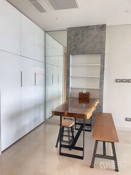 Condominium for rent in Pathum Wan, Bangkok - Dining or study area with solid wood table, bench seating and glossy built-in cabinets.