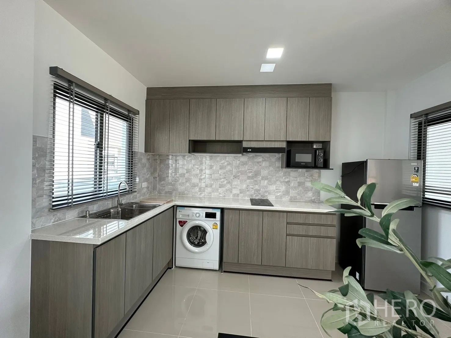联排别墅 for rent in Bang Phli, Samut Prakan - L型厨房带石纹挡板、水槽和洗衣机。