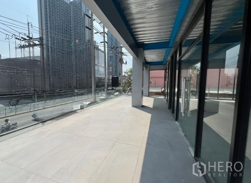 Retail Space for rent in Huai Khwang, Bangkok - Shaded terrace and wide frontage overlooking a busy main road with city towers beside full-height shopfronts.