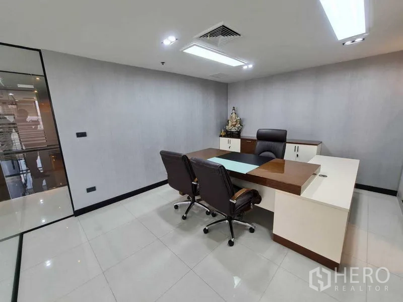 Office Space for rent - Executive office with an L-shaped desk, two guest chairs and recessed lighting in a modern Bangkok workspace.