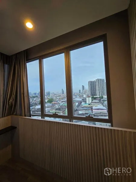 Condominium for rent - Wide window presenting a high-floor view of the Bangkok skyline.