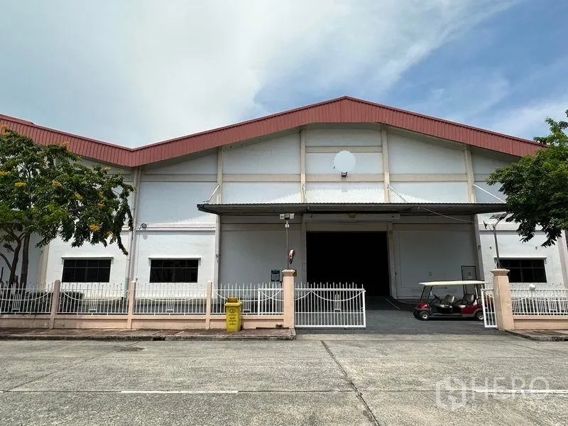 Warehouse for rent in Bang Sao Thong, Samut Prakan - Front elevation of the warehouse with roller shutter entrance, perimeter fence and paved frontage.