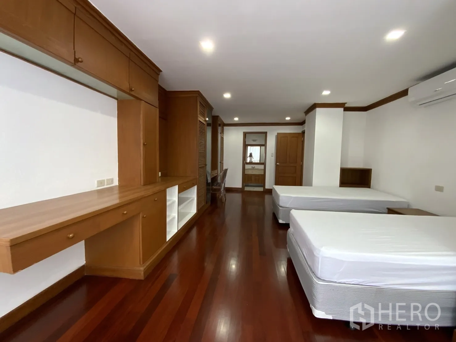 公寓 出租在Watthana, Bangkok - 卧室内两张单人床，大量木质柜体与木地板。