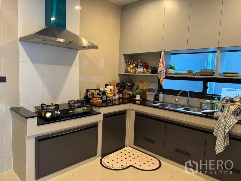 Detached House for rent in Bang Kapi, Bangkok - Enclosed L‑shaped kitchen with gas cooktop, range hood, sink and ample cabinetry.