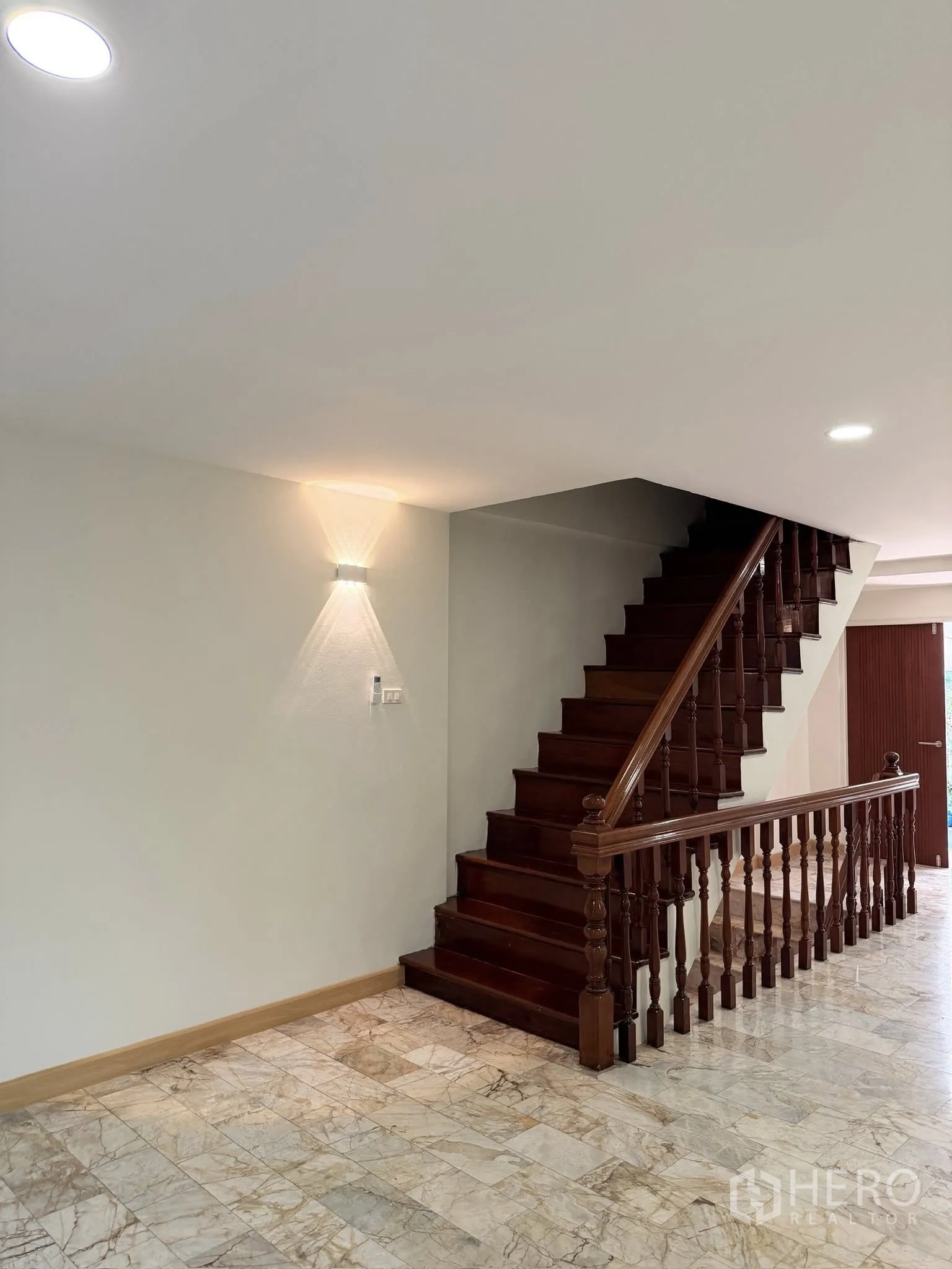 Townhouse for rent or sale in Yan Nawa, Bangkok - Side view of polished wooden staircase and illuminated wall.
