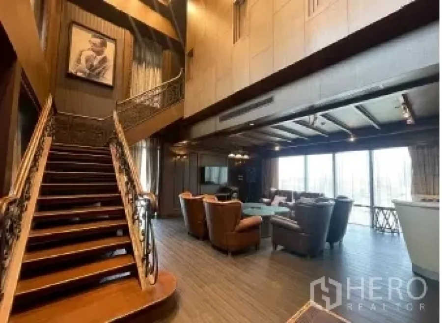 Retail Space for rent - Double-height retail interior with wooden staircase, lounge seating, chandelier lighting, and floor-to-ceiling windows.