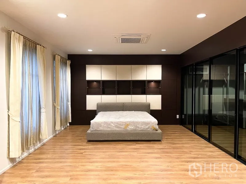 Townhouse for rent in Yan Nawa, Bangkok - Large master bedroom with wood floors, feature wall paneling, bed frame and glass walk-in closet.