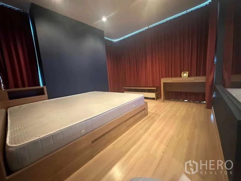 Condominium for sale in Phaya Thai, Bangkok - Spacious master bedroom with wood floors and deep red curtains.