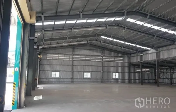 Warehouse for rent in Mueang Nonthaburi, Nonthaburi - Open-plan storage area with high ceiling, metal structure, and natural light panels.