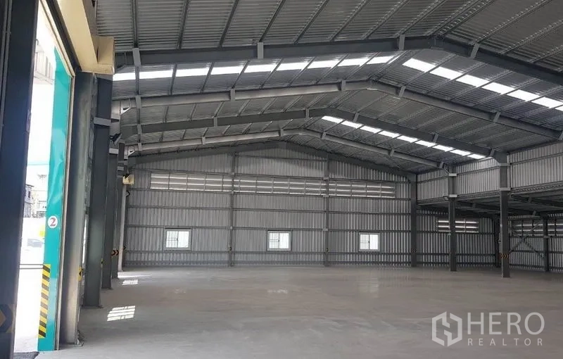 Warehouse for rent in Mueang Nonthaburi, Nonthaburi - Open-plan storage area with high ceiling, metal structure, and natural light panels.