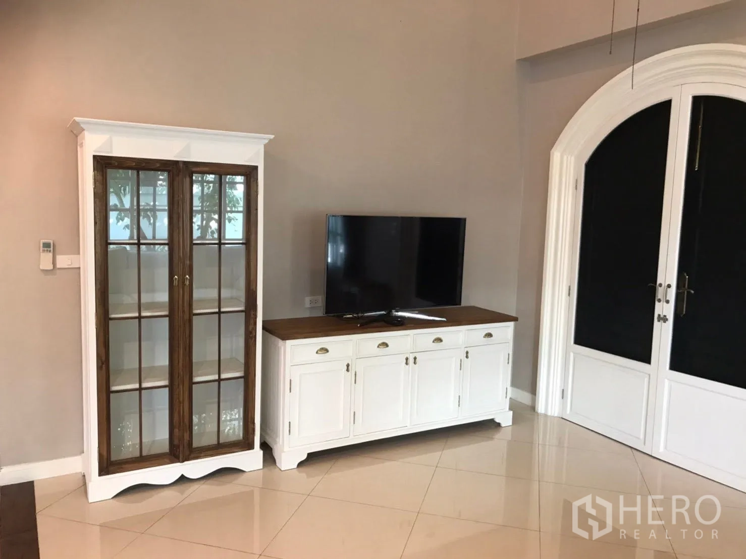 บ้านเดี่ยว for rent in Mueang Samut Prakan, Samut Prakan - มุมห้องนั่งเล่นมีตู้โชว์กระจกและตู้วางทีวีข้างประตูโค้งคู่