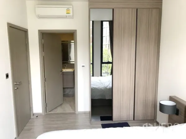 Condominium for rent in Watthana, Bangkok - Bedroom with built-in wardrobe, air conditioner, and door to the bathroom.