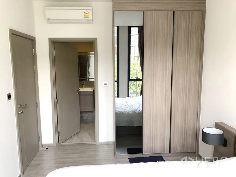 Condominium for rent in Watthana, Bangkok - Bedroom with built-in wardrobe, air conditioner, and door to the bathroom.