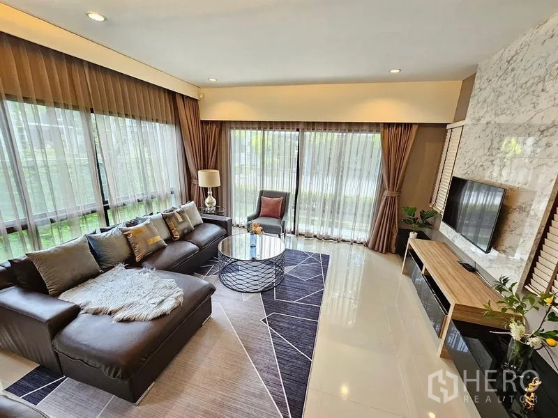 บ้าน ให้เช่าในPrawet, Bangkok - ห้องนั่งเล่นโซฟาหนังทรง L หน้าต่างสูงเต็มบานและผ้าม่านโปร่ง