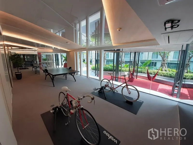 公寓 出租或出售在Watthana, Bangkok - 公寓设施区，设室内骑行训练台、乒乓球台与花园景。