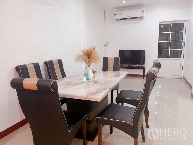Townhouse for rent in Huai Khwang, Bangkok - Dining area with six chairs, marble-top table and wall-mounted air conditioner.