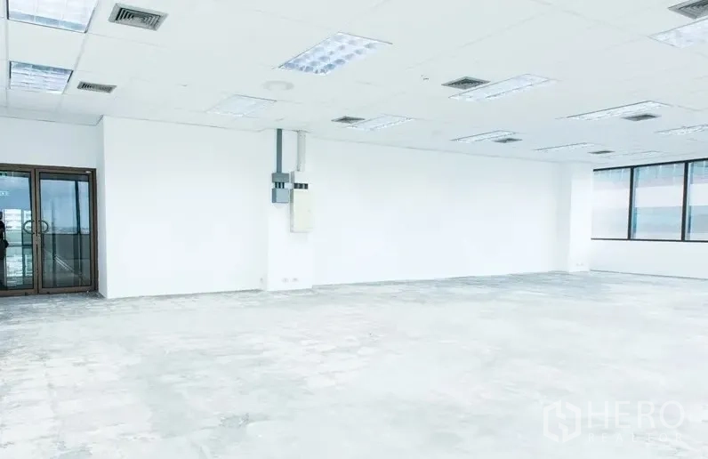 Office Space for rent in Bang Na, Bangkok - Unfurnished office interior with glass double entry doors, electrical panel, white walls, and grid ceiling lighting.