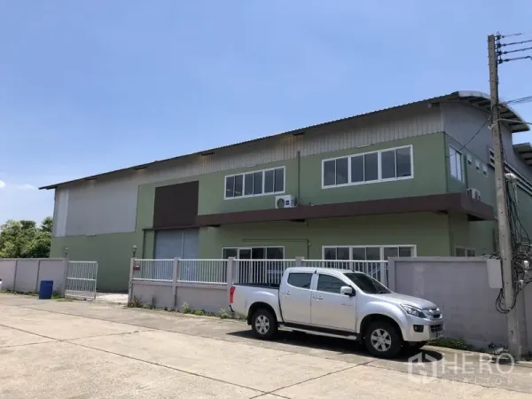 Factory for rent in Pathum Thani - Front exterior of factory showing fence, parking and loading roller shutter.